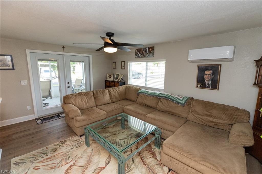 Image 4: Living area featuring wood-finish flooring, light neutral wall paint, and a ceiling fan with integrated lighting