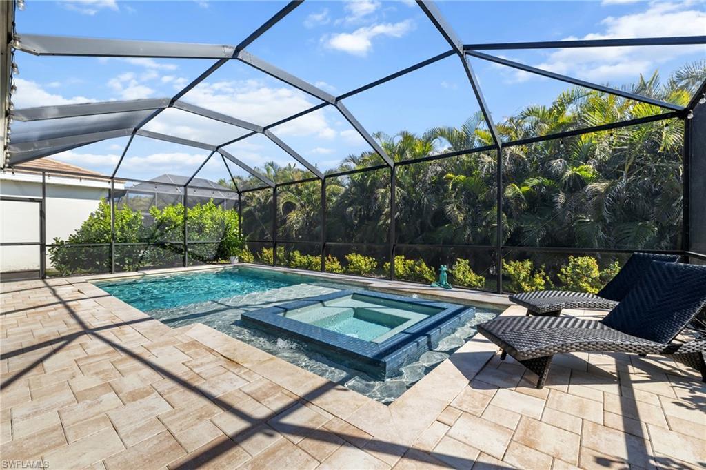 Image 2: View of pool with a lanai, a sunroom, a pool with connected hot tub, and a patio area