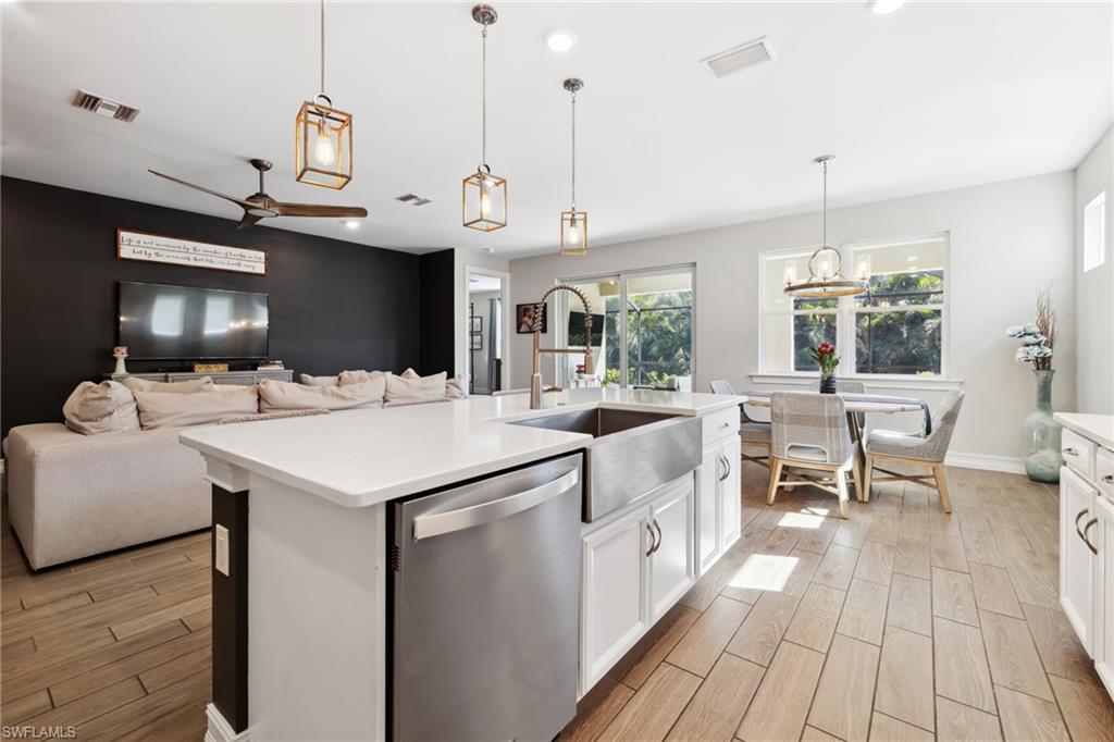 Image 3: Kitchen with white cabinets, stainless steel dishwasher, wood finish floors, open floor plan, and ceiling fan