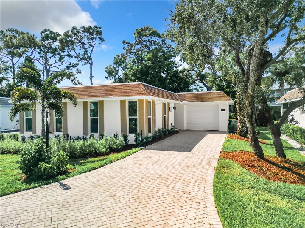 Image 1: View of front facade featuring a front yard and a garage