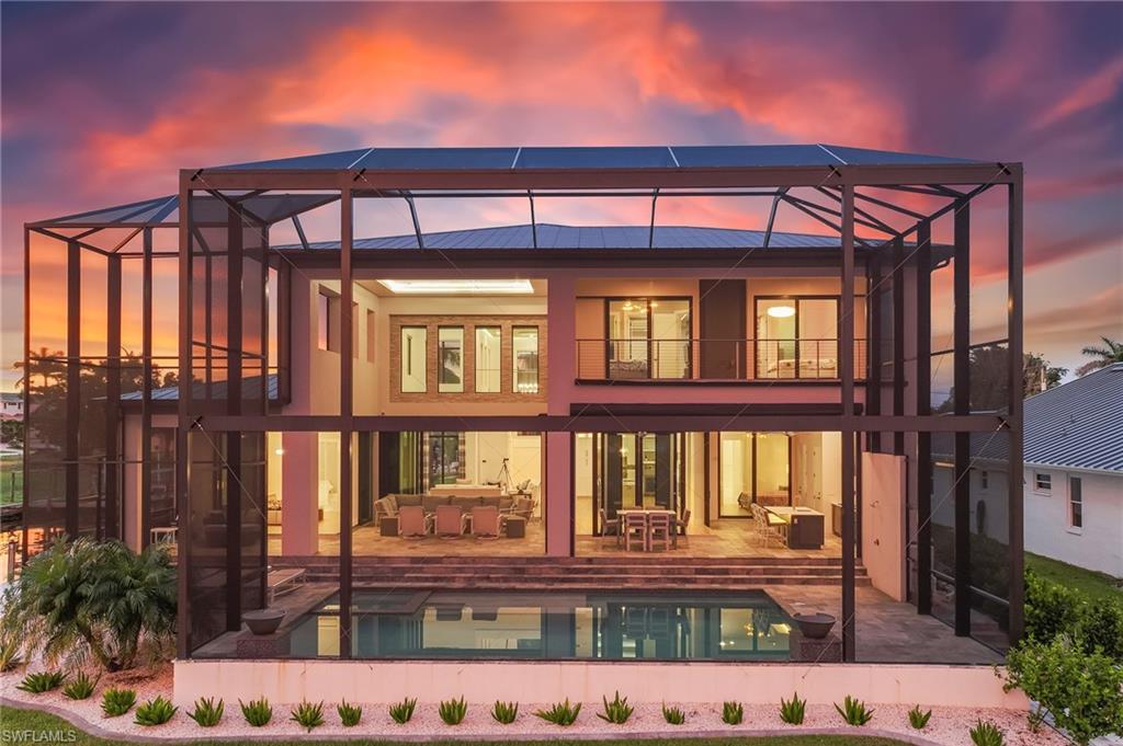 Image 1: Back of house at dusk with a lanai and a water view