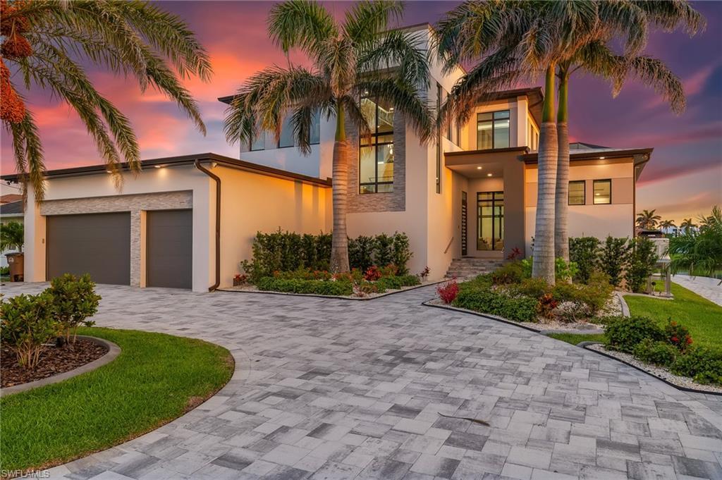 Image 2: Modern home featuring decorative driveway, stucco siding, and an attached garage