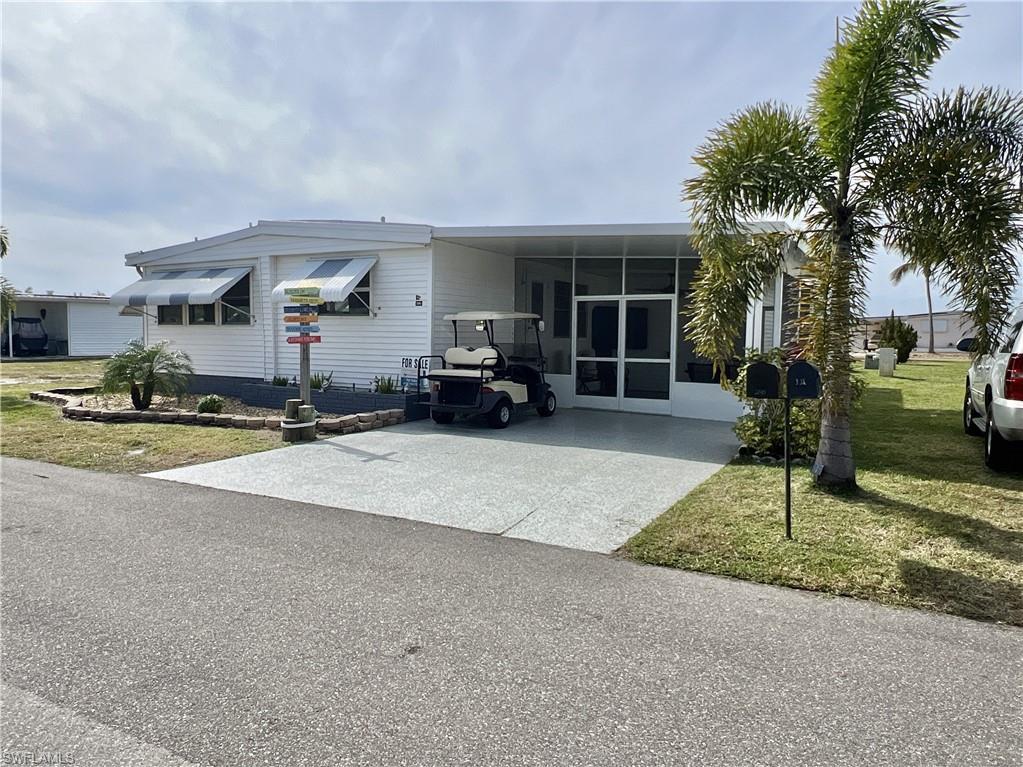 Image 3: View of front of home with a front lawn, concrete/epoxy driveway, lanai, and a carport