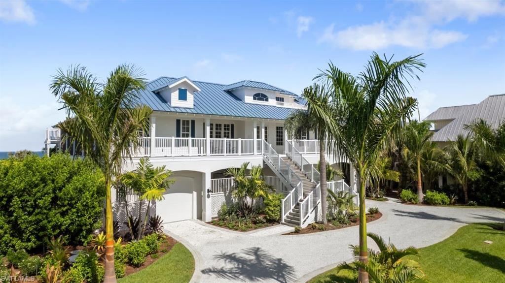 Image 2: Coastal inspired home featuring gravel driveway, a metal roof, stairs, an attached garage, and stucco siding