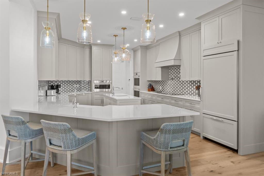 Image 3: Kitchen featuring a peninsula, a breakfast bar area, light stone countertops, hanging light fixtures, and recessed lighting