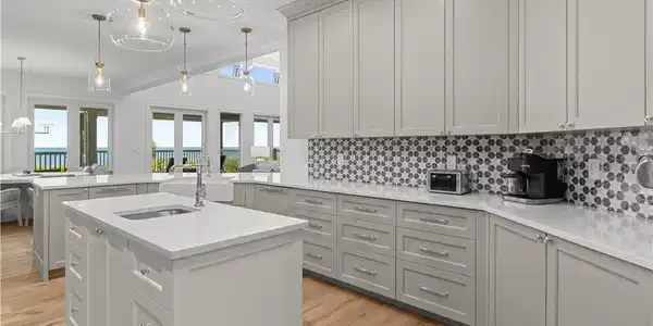 Image 4: Kitchen with decorative light fixtures, backsplash, a peninsula, light stone countertops, and light wood finished floors