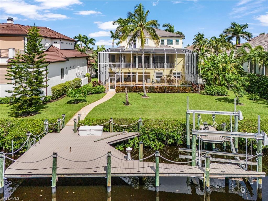 Image 3: Rear view of house featuring boat lift, a yard, a sunroom, a lanai, and a water view