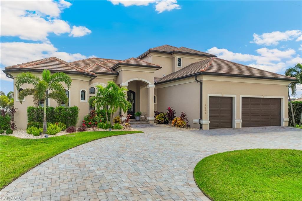 Image 2: Mediterranean / spanish house featuring stucco siding, french doors, decorative driveway, a front lawn, and a garage