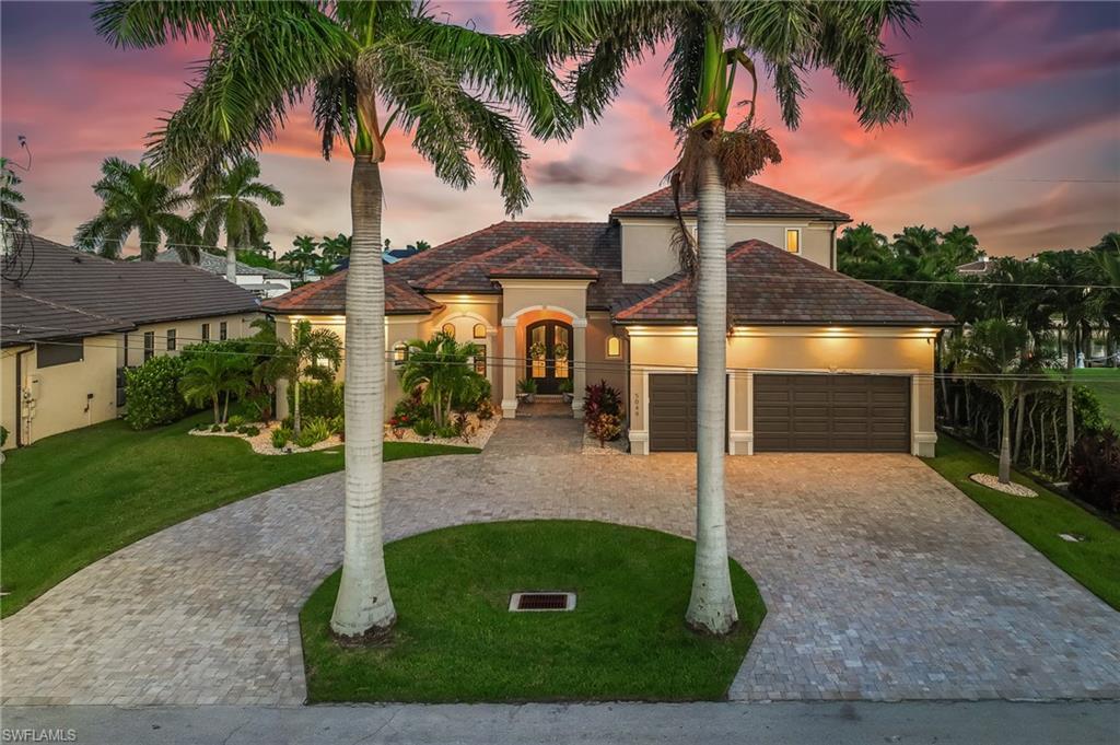 Image 4: Mediterranean / spanish-style home with stucco siding, decorative driveway, a front lawn, a garage, and french doors