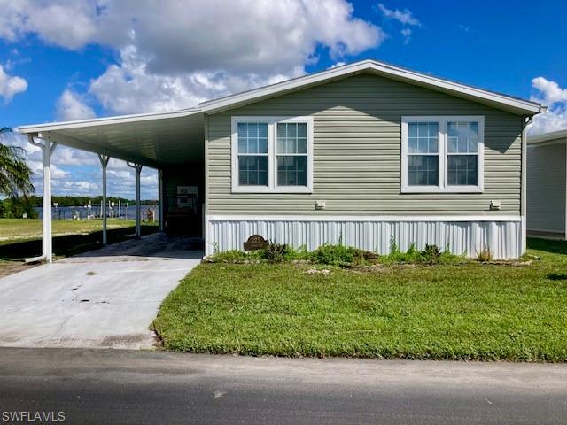 Image 1: Manufactured / mobile home featuring a front lawn, driveway, and a carport