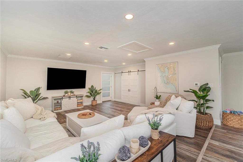 Image 2: Living room with recessed lighting, attic access, wood finished floors, a barn door, and crown molding