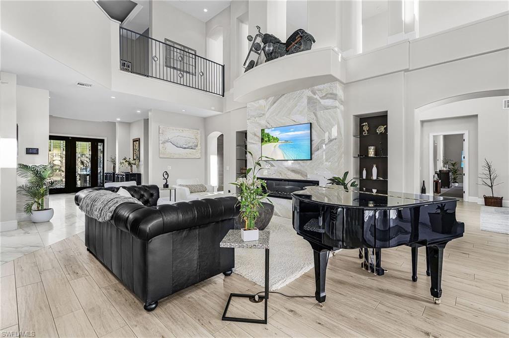 Image 4: Living area featuring light marble finish floors, arched walkways, recessed lighting, and a towering ceiling