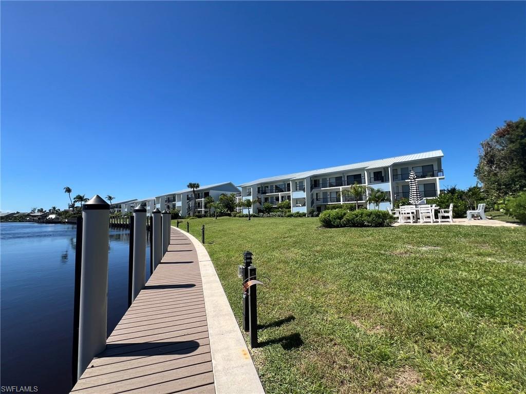 Image 4: Dock featuring a lawn and a water view