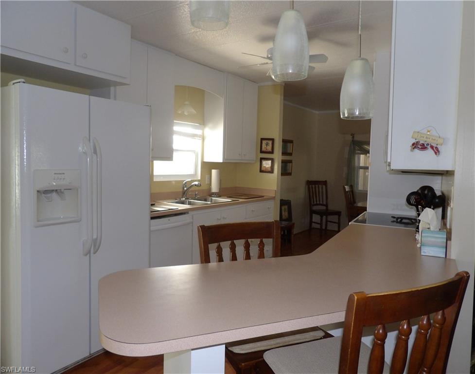 Image 4: Kitchen featuring white appliances, a peninsula, a kitchen breakfast bar, and light countertops