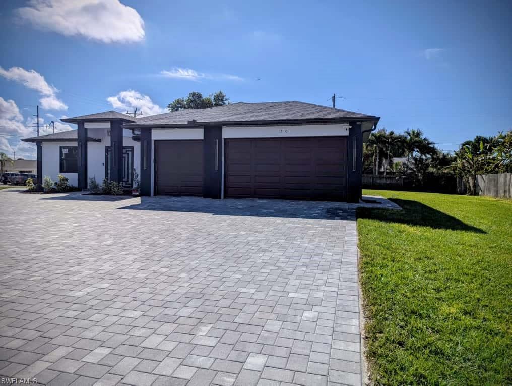 Image 4: View of front of house featuring decorative driveway, a front lawn, stucco siding, and an attached garage