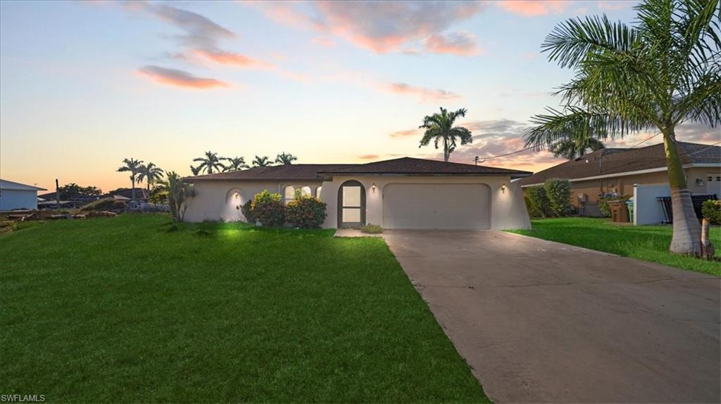 Image 1: Ranch-style house with stucco siding, driveway, a yard, and a garage
