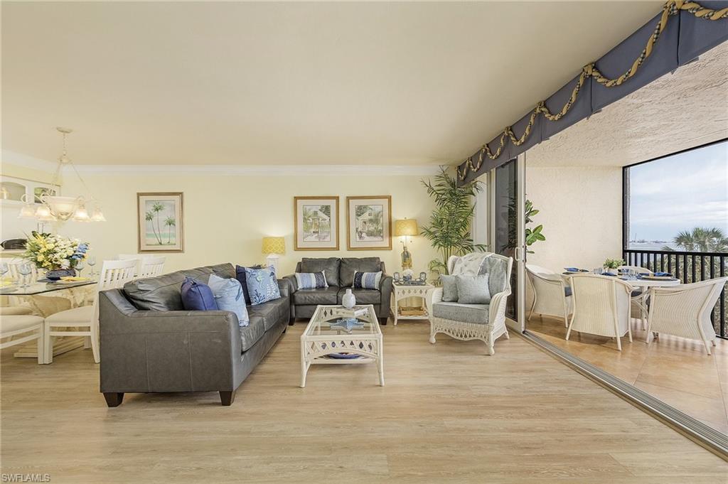 Image 4: Living room with light hardwood / wood-style floors, crown molding, and a chandelier