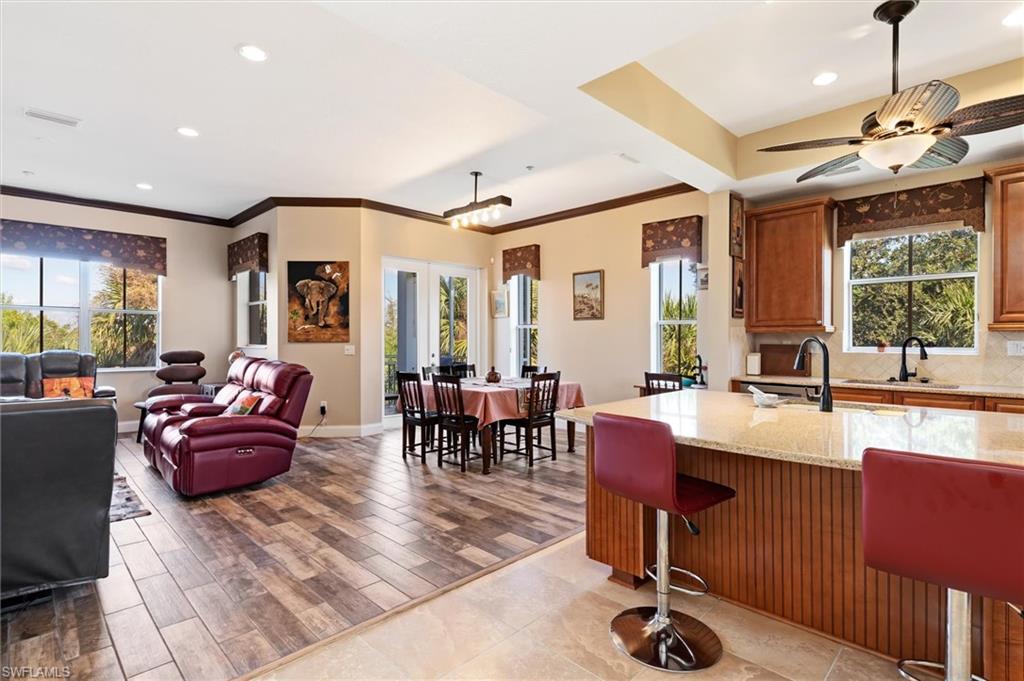 Image 3: Kitchen featuring light stone counters, a breakfast bar, crown molding, brown cabinetry, and open floor plan