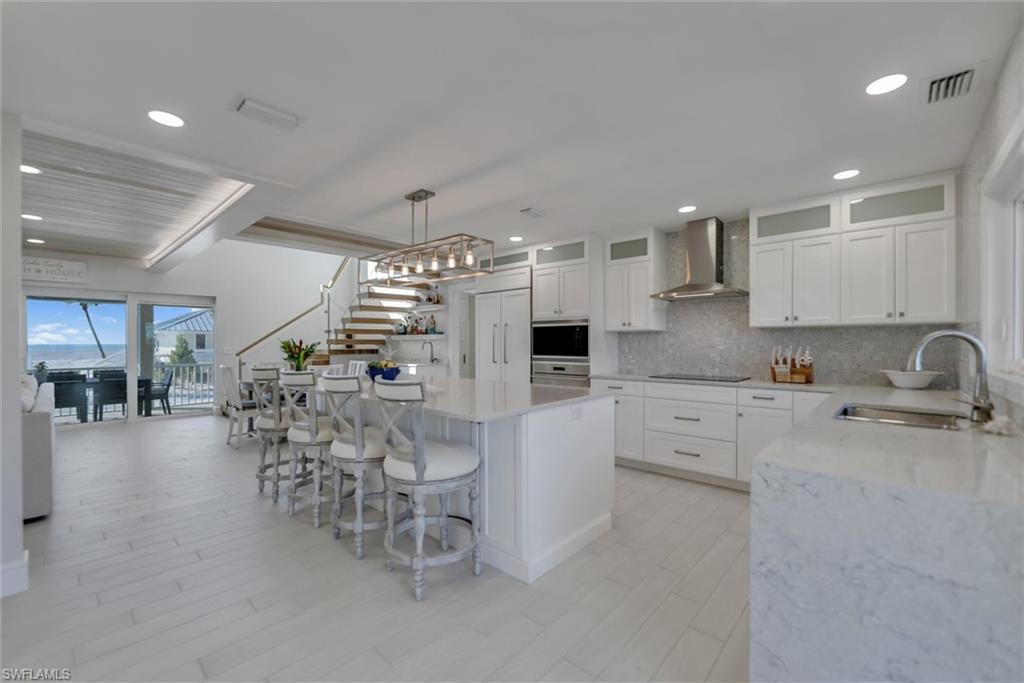 Image 2: Kitchen featuring light stone countertops, plenty of natural light, white cabinetry, a kitchen island, and recessed lighting