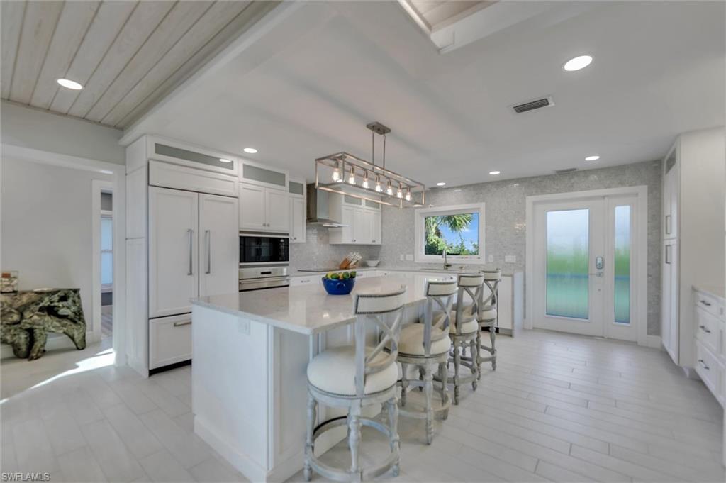 Image 3: Kitchen featuring a kitchen breakfast bar, hanging light fixtures, white cabinets, a center island, and built in appliances