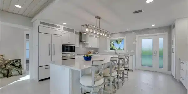 Image 3: Kitchen featuring a kitchen breakfast bar, hanging light fixtures, white cabinets, a center island, and built in appliances
