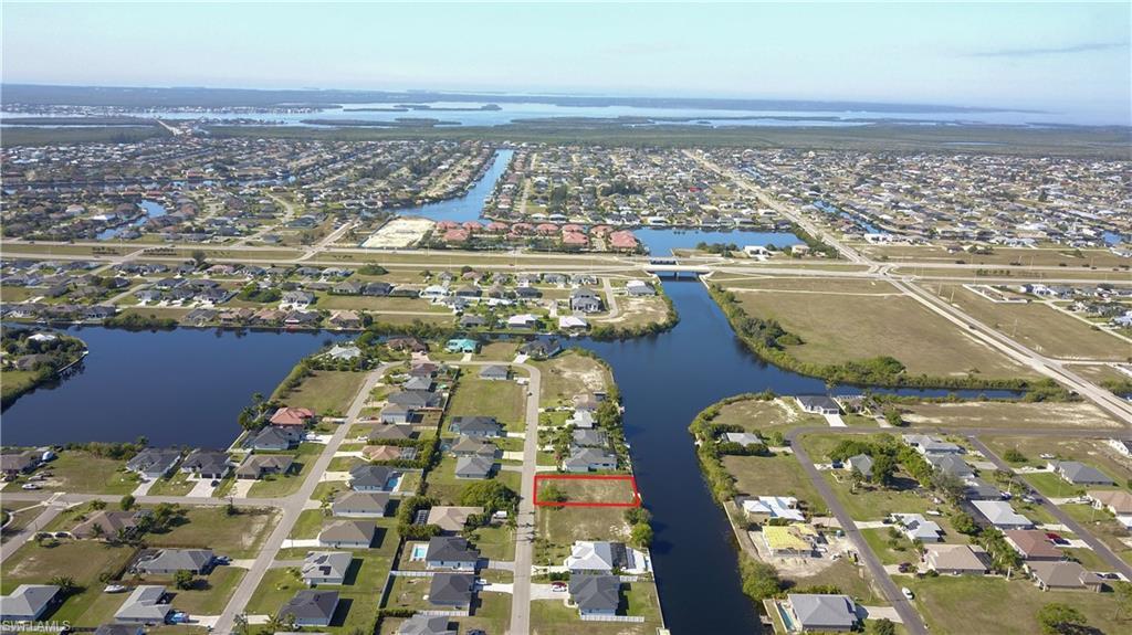 Image 1: Aerial view of property and surrounding area featuring nearby suburban area, property parcel outlined, and a nearby body of water