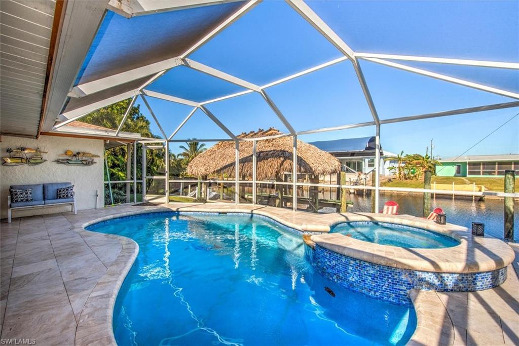 Image 3: View of pool with a sunroom, a pool with connected hot tub, a patio area, glass enclosure, and a water view
