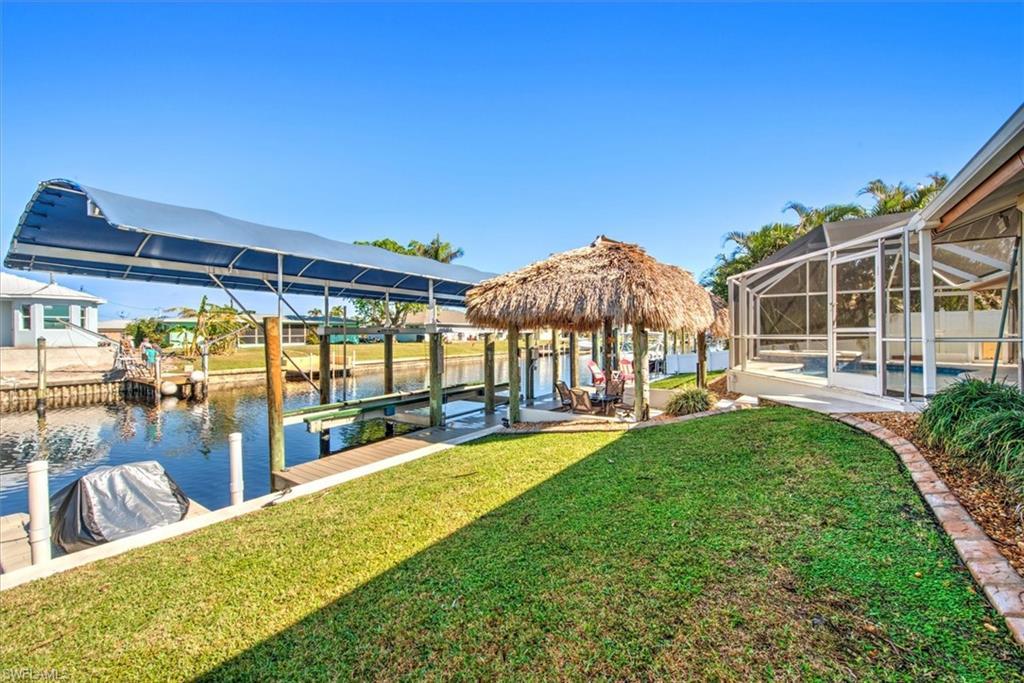 Image 4: Dock area featuring a sunroom, boat lift, a lanai, a water view, and a swimming pool