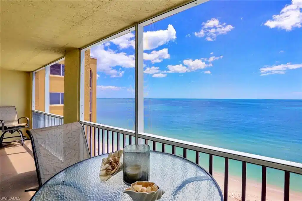 Image 1: Balcony featuring a sunroom, outdoor dining area, and view of water and beach