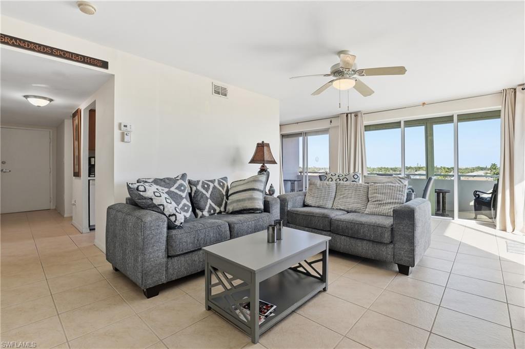 Image 3: Living area with light tile patterned floors and ceiling fan