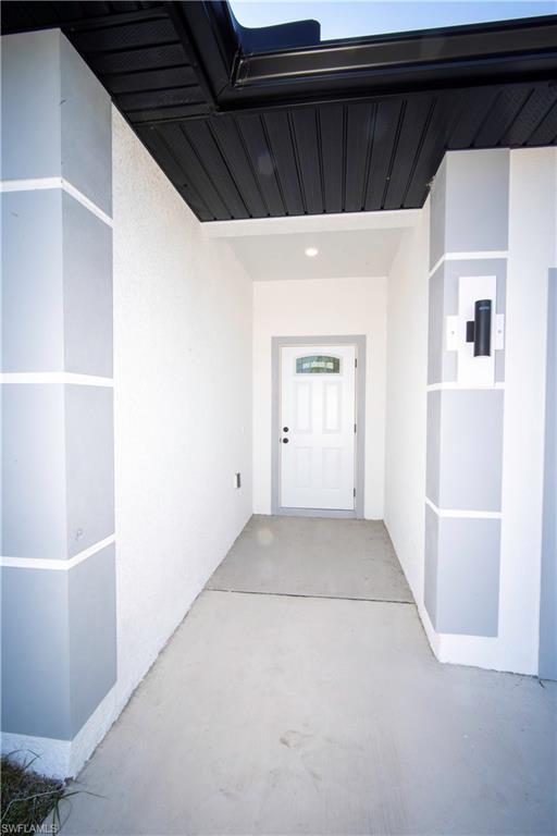 Image 2: View of exterior entry featuring stucco siding and a patio area