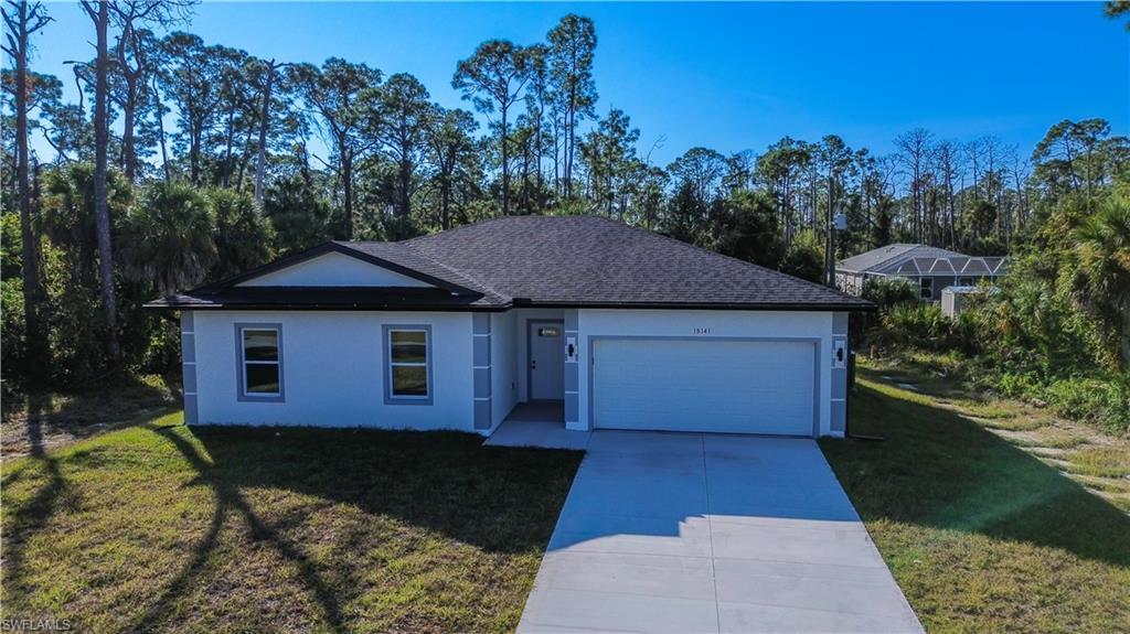 Image 3: Single story home featuring a front lawn, driveway, stucco siding, an attached garage, and view of scattered trees