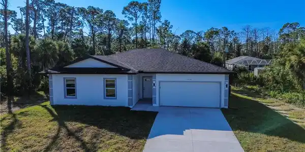 Image 3: Single story home featuring a front lawn, driveway, stucco siding, an attached garage, and view of scattered trees