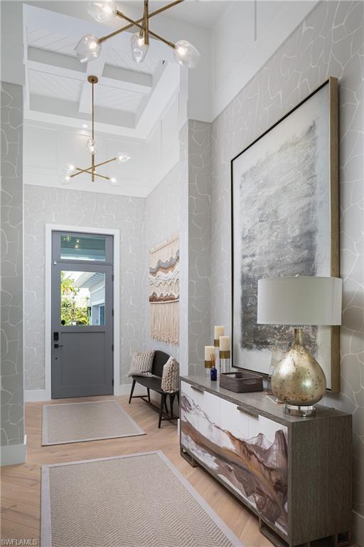 Image 2: Foyer with beam ceiling, a notable chandelier, coffered ceiling, and wood-type flooring
