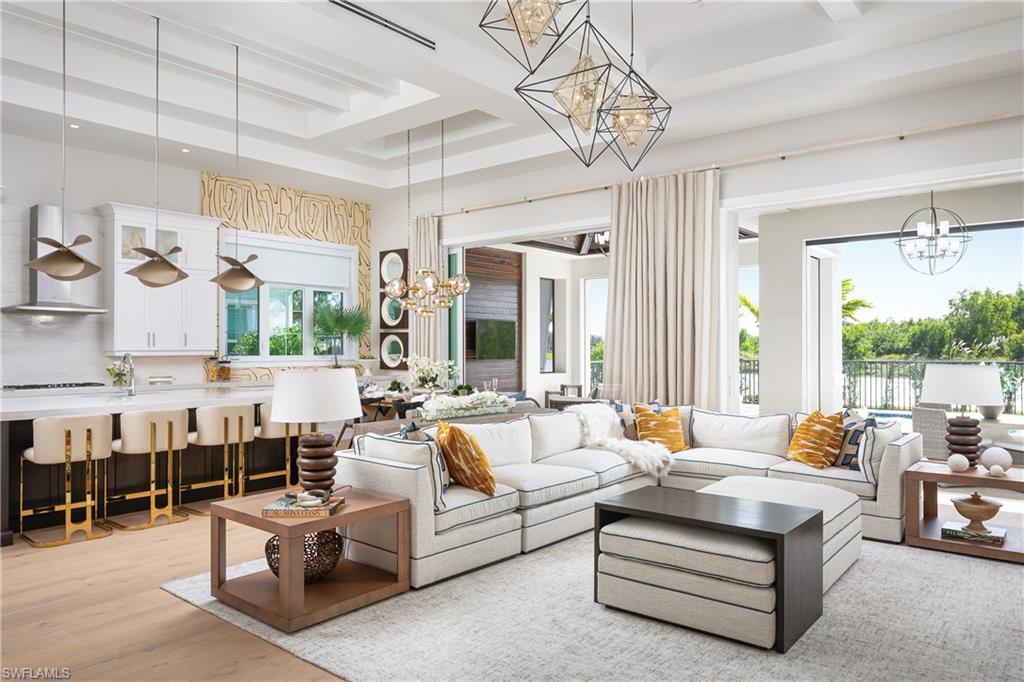 Image 3: Living room with a raised ceiling, light hardwood / wood-style floors, and an inviting chandelier