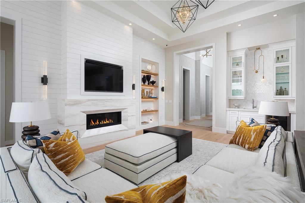 Image 4: Living room with a fireplace, light hardwood / wood-style flooring, built in shelves, a chandelier, and sink