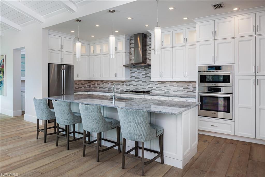Image 3: Kitchen with wall chimney exhaust hood, hardwood / wood-style flooring, pendant lighting, and appliances with stainless steel finishes
