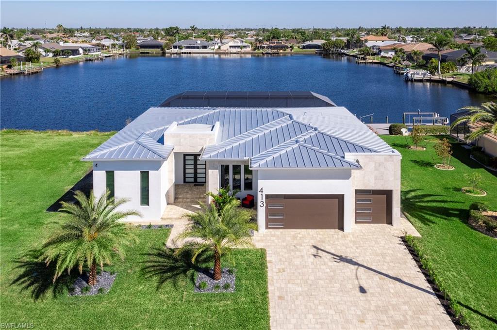 Image 1: View of front of property with stucco siding, a water view, decorative driveway, a residential view, and an attached garage
