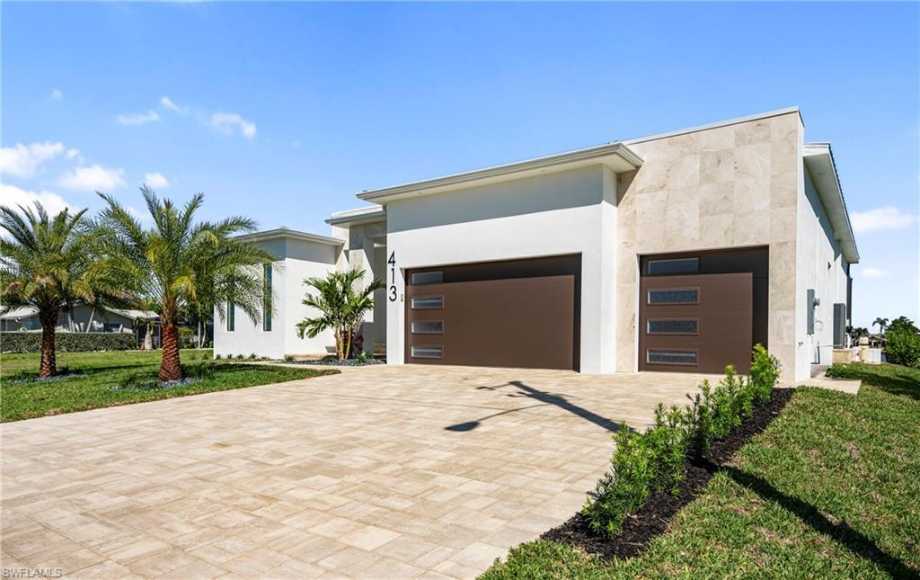 Image 3: Modern home with a garage, decorative driveway, a front lawn, and stucco siding