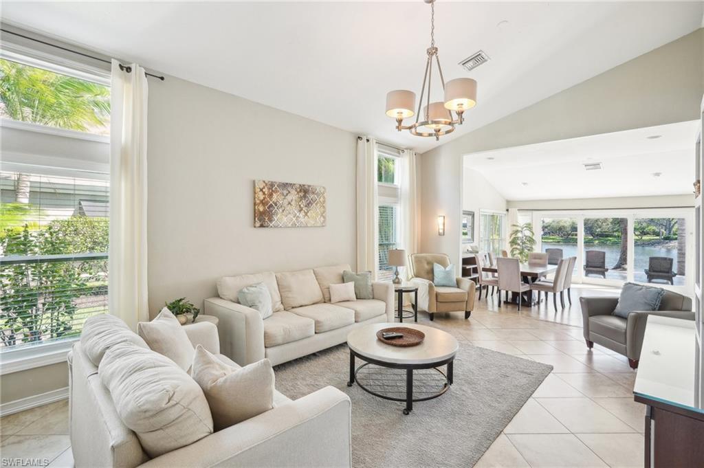 Image 4: Living room featuring lofted ceiling, light tile patterned flooring, visible vents, plenty of natural light, and an inviting chandelier