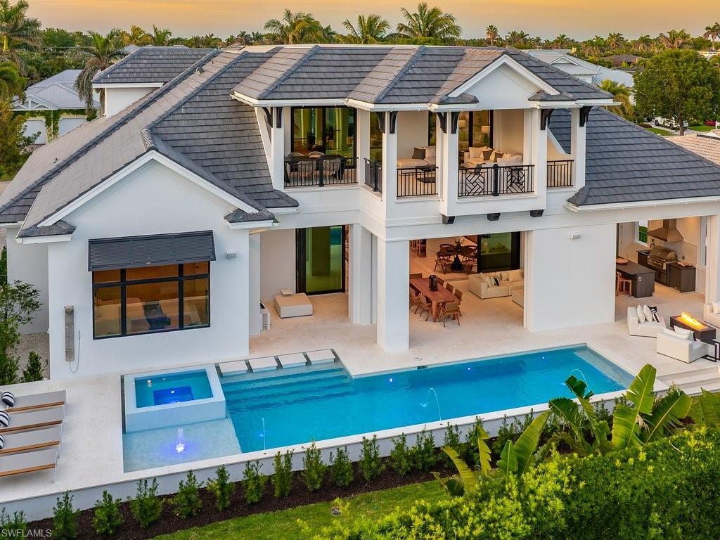 Image 2: Rear view of house featuring an outdoor pool, stucco siding, a tiled roof, a balcony, and a patio area