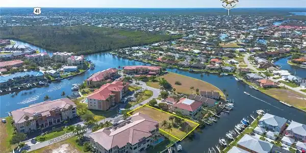 Image 4: Aerial view of residential area with a nearby body of water and property parcel outlined