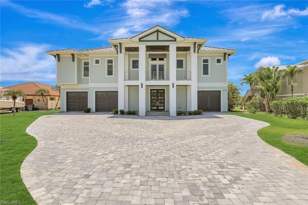 Image 1: View of front of house with a garage, a standing seam roof, and decorative driveway