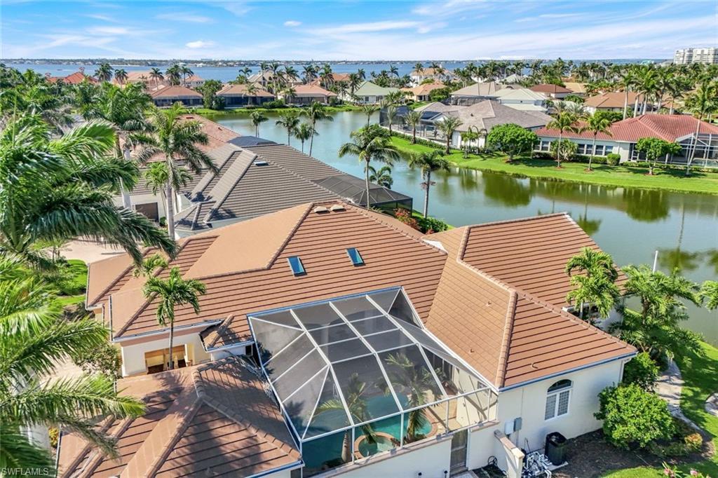 Image 4: View of front facade featuring a water view, an attached garage, a tile roof, a residential view, and stucco siding