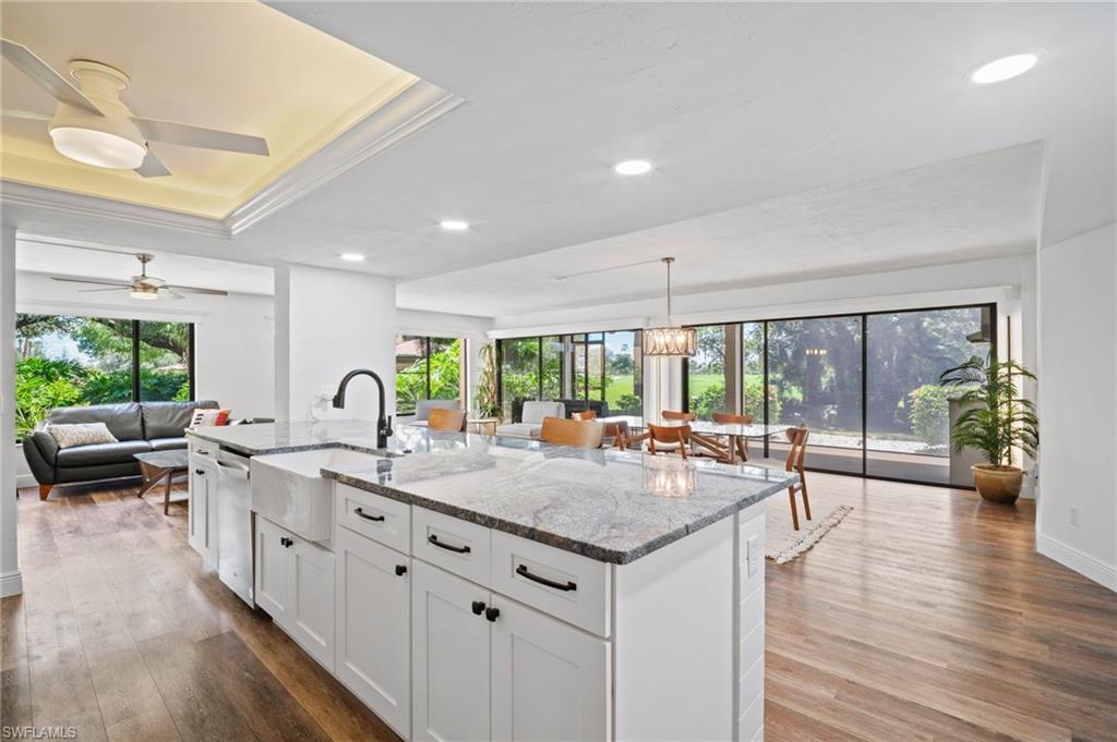 Image 2: Kitchen featuring light stone countertops, white cabinets, recessed lighting, a center island with sink, and open floor plan