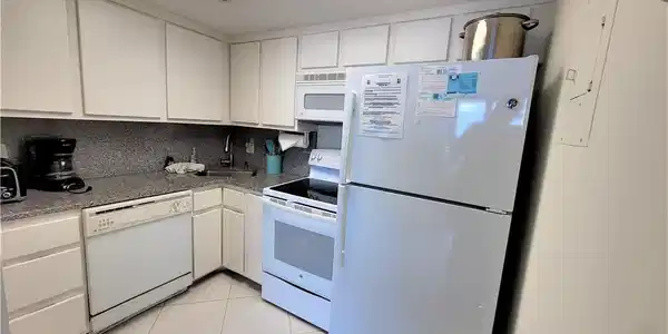 Image 3: Kitchen with white appliances, white cabinets, backsplash, and light tile patterned flooring