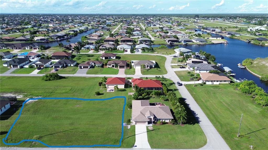 Image 3: Aerial view of residential area with a large body of water and property parcel outlined