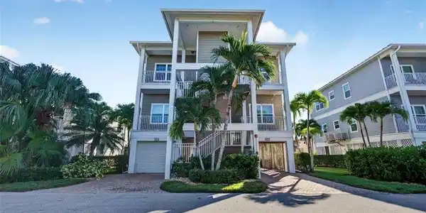 Image 3: Beach home with stairway, decorative driveway, a balcony, and an attached garage