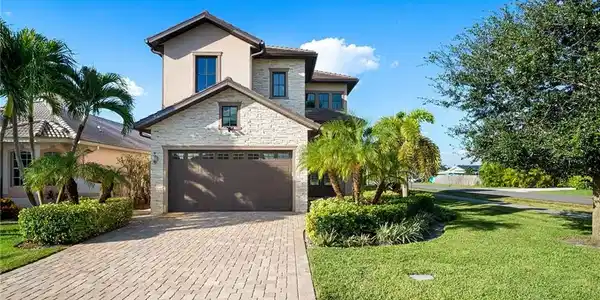 Image 2: View of front of home featuring stone siding, a front yard, decorative driveway, a garage, and stucco siding