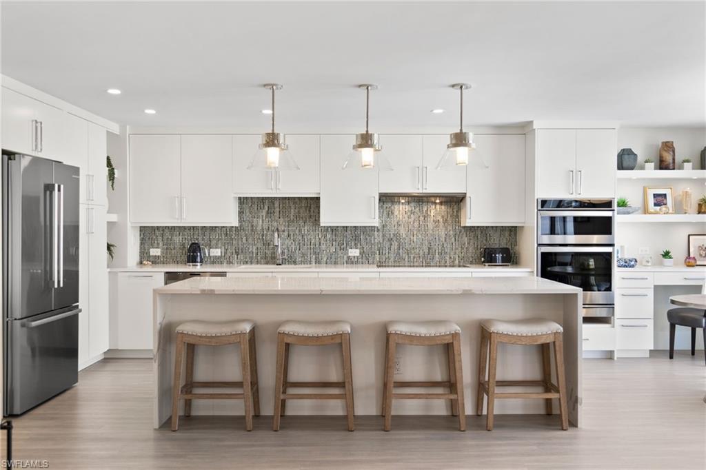 Image 4: Kitchen with open shelves, white cabinets, a kitchen breakfast bar, stainless steel appliances, and recessed lighting